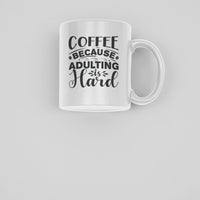 Funny coffee mug with bold black text saying 'Coffee Because Adulting is Hard', 11 oz ceramic cup for coffee lovers.