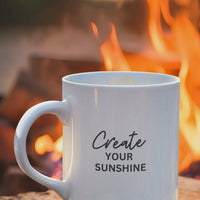 Create Your Sunshine motivational mug on a wooden surface, featuring bold text and a warm campfire background.