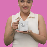 Woman holding a stylish sassy mug with gold sparkle text against a pink background, perfect for coffee lovers.