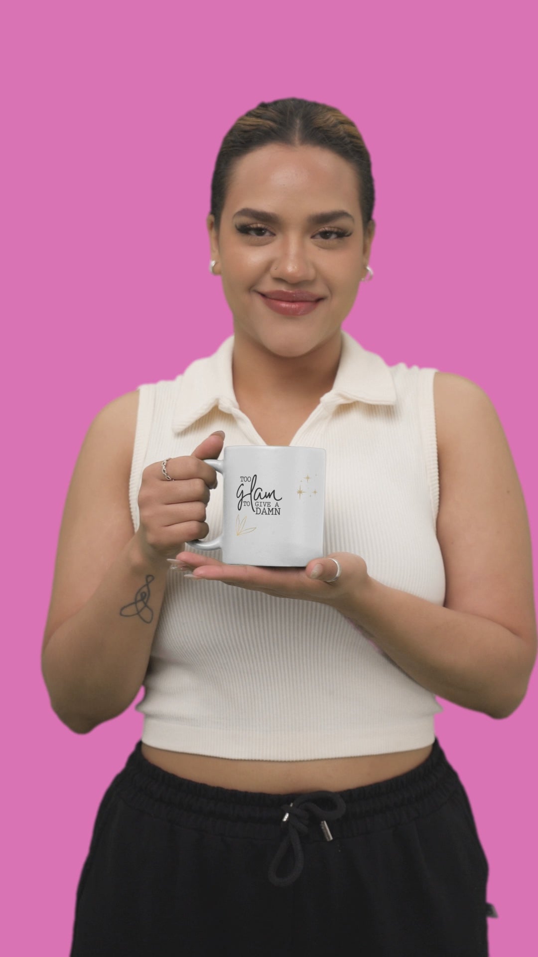 Woman holding a stylish sassy mug with gold sparkle text against a pink background, perfect for coffee lovers.